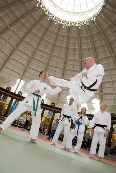 Dr Charles Spring wearing a karate gi, demonstrating a flying kick